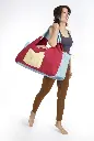 Woman holding an extra Large burgundy gym bag on her side that covers her upper half body.webp